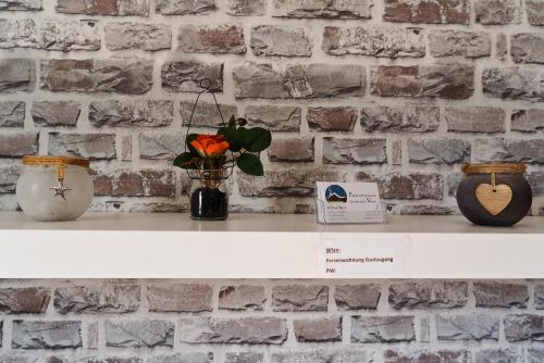a white shelf with two vases and a brick wall at Zimmervermietung Vock in Eschwege