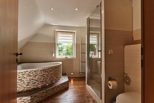 a bathroom with a tub and a glass shower at Zimmervermietung Vock in Eschwege