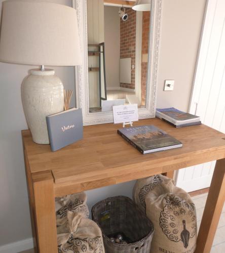 a table with a lamp and a mirror at The Barn, Boutique Self-Catering Apartment - Belvoir Suite in Allington