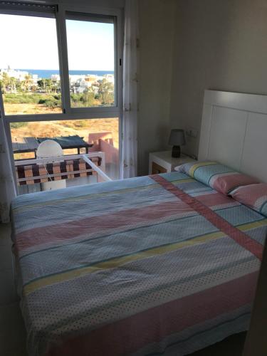a bedroom with a bed and a large window at Atico con piscina privada y vistas al mar in Vera