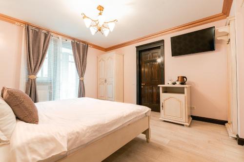 a bedroom with a white bed and a television at Vila Genia in Câmpulung Moldovenesc