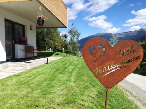 ein Herzschild im Gras vor einem Haus in der Unterkunft Bergperle Apartments & Mountain Sport in Fliess