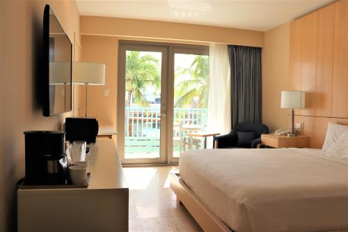 a hotel room with a bed and a balcony at The Mill Resort and Suites in Palm-Eagle Beach