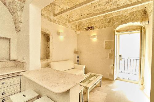 ein weißes Zimmer mit einem Tisch und einem Fenster in der Unterkunft Casa Antica Roma in Ostuni