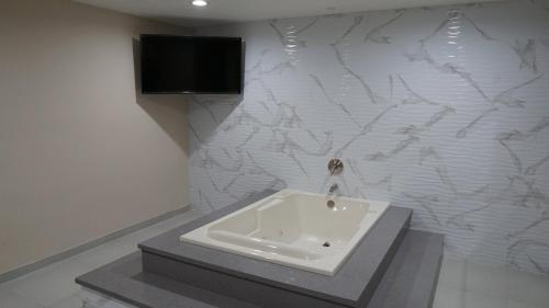 baño con lavabo y TV en la pared en Sea Breeze Inn - LAX Airport, Los Angeles, en Inglewood