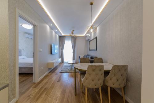Apartments Centrale 28 في بودغوريتسا: غرفة طعام مع طاولة وكراسي وغرفة نوم