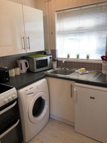 uma cozinha com uma máquina de lavar roupa e um lavatório em St Marks em Northfleet