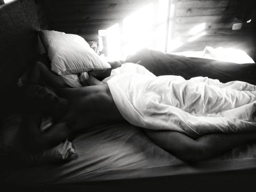 a person laying on a bed under a blanket at The Naked House - Hotel Nudista in Nemocón