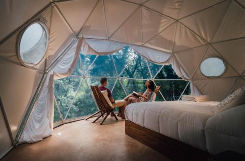 2 personas sentadas en sillas en una habitación con una gran ventana en Ku kuk Glamping, en Chemuyil