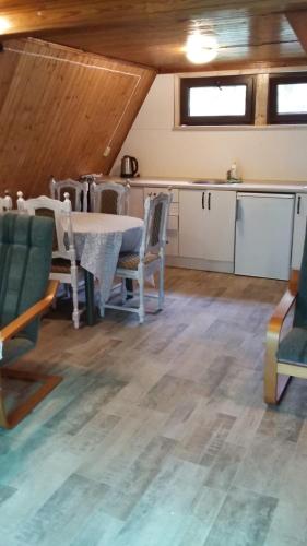 Habitación con mesa, sillas y cocina. en Domek pod świerkami 2 en Skorzęcin