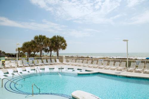 a swimming pool with lounge chairs and the beach at Ocean Escape Condos in Myrtle Beach