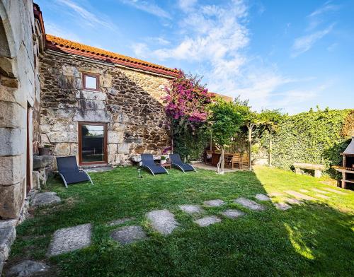 a yard with chairs and a stone house at Pazo de Lemaio in Laracha