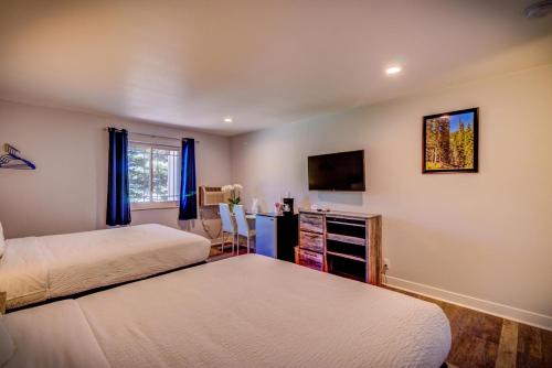 a bedroom with two beds and a tv on the wall at RiverWalk Inn in Pagosa Springs