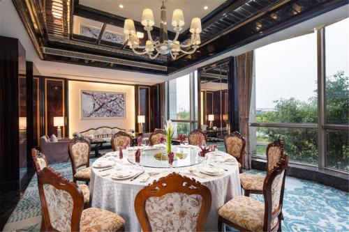 une salle à manger avec une table, des chaises et un lustre dans l'établissement Ramada Plaza Qiandeng Kunshan, à Kunshan