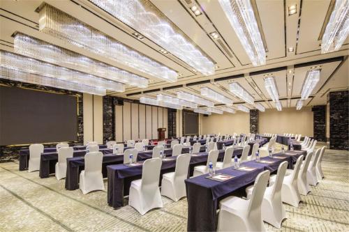 a large banquet hall with tables and white chairs at Ramada Plaza Qiandeng Kunshan in Kunshan