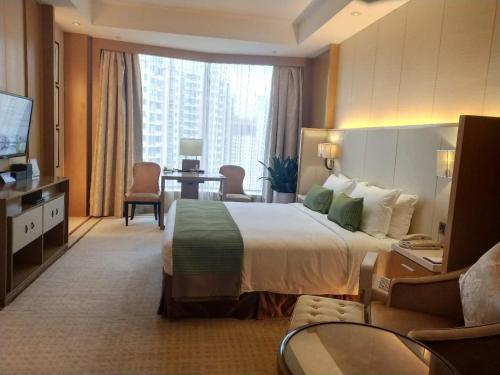 a hotel room with a large bed and a living room at Ramada Plaza Qiandeng Kunshan in Kunshan