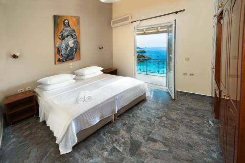 a bedroom with a large white bed and a balcony at Platakia Blu in Paleokastritsa