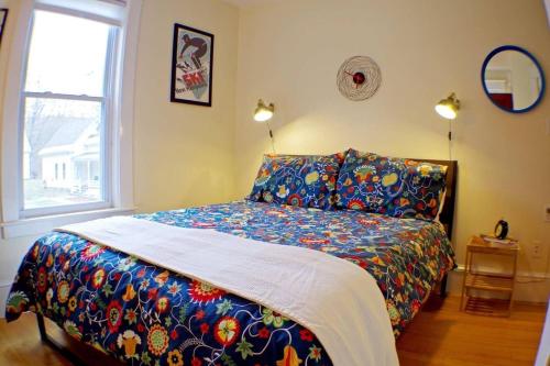 a bedroom with a bed with a colorful comforter and a window at The Craftsman Farmhouse with Modern Flair in Bethlehem