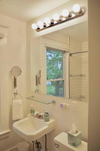 a white bathroom with a sink and a mirror at The Craftsman Farmhouse with Modern Flair in Bethlehem