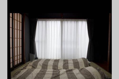 a bedroom with a bed in front of a window at Iida Accommodation in Iida