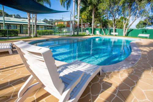 a swimming pool with two white chairs next to it at BIG4 Batemans Bay at Easts Riverside Holiday Park in Batemans Bay