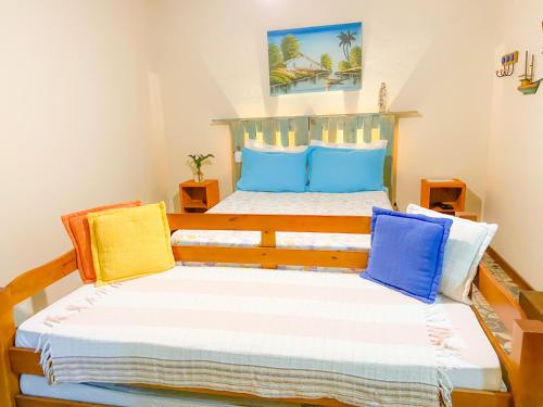 a bedroom with two beds with blue and yellow pillows at Casa Aluguel Abraão 3,Ilha grande in Abraão