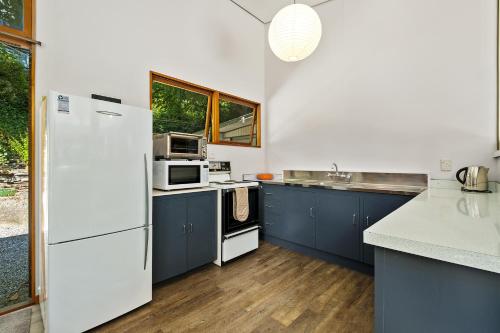 a kitchen with blue cabinets and a white refrigerator at Merioneth Retreat - Arrowtown Holiday Home in Arrowtown