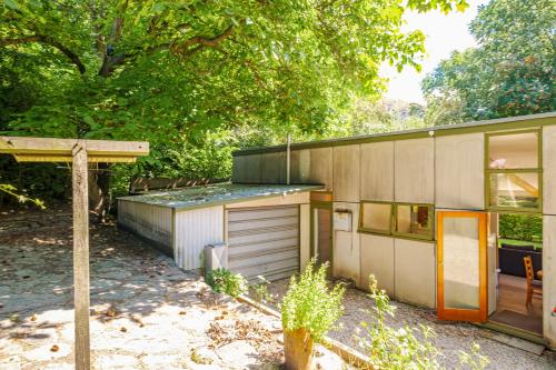 a house with a garage next to a tree at Merioneth Retreat - Arrowtown Holiday Home in Arrowtown