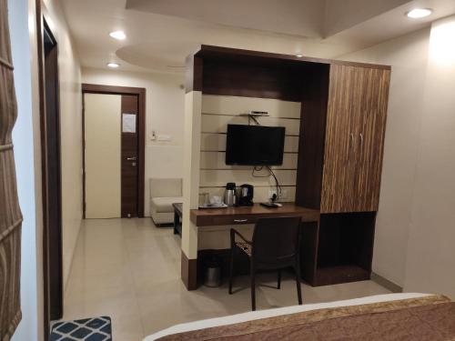 a hotel room with a desk and a television at Starlit Select Nirvana in Varanasi