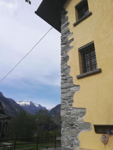 a building with a window and mountains in the background at Rifugio Monte Zeus in Baceno