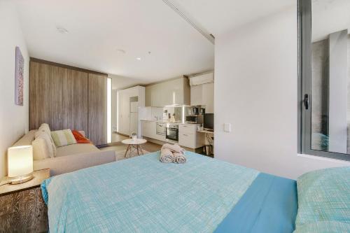 a bedroom with a bed and a living room at A Lovely Studio Next to Southern Cross in Melbourne