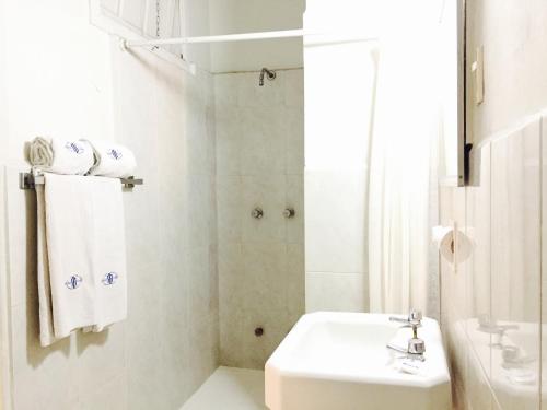 a white bathroom with a sink and a shower at Hotel Isabel in Mexico City