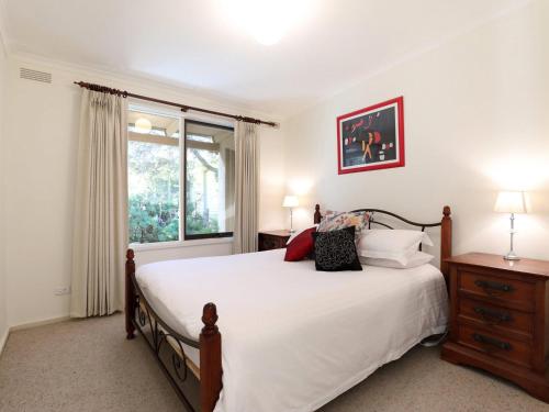 a bedroom with a bed with white sheets and a window at Back Beach Hideaway in Blairgowrie