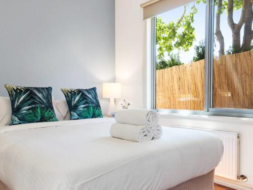 a bedroom with a large white bed with a window at Bella Vista in McCrae