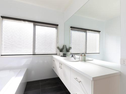 a white bathroom with two sinks and two windows at Bluetopia in Rye