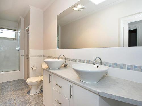a bathroom with two sinks and a toilet and a mirror at Poolside Sorrento in Sorrento
