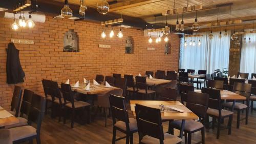 un restaurant avec des tables et des chaises en bois et un mur en briques dans l'établissement Mehana apartmani, à Leskovac