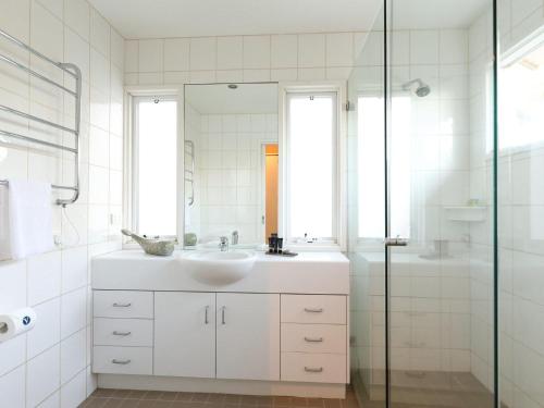 a white bathroom with a sink and a shower at The Beach House in Sorrento
