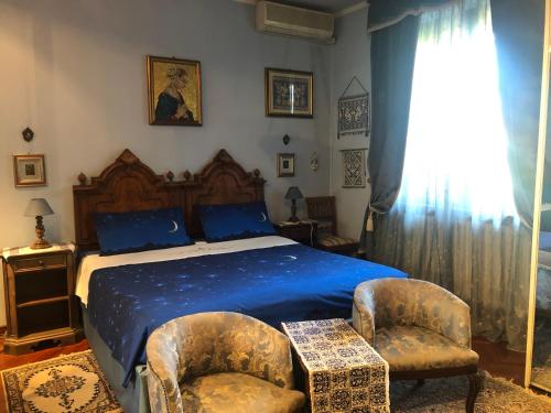 a bedroom with a bed with blue sheets and two chairs at B&B Les Fleurettes in Lomazzo