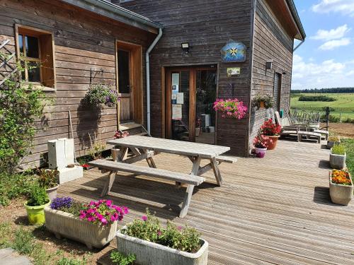a wooden deck with a picnic table and some flowers at La Rose des Vents in Les Vastres