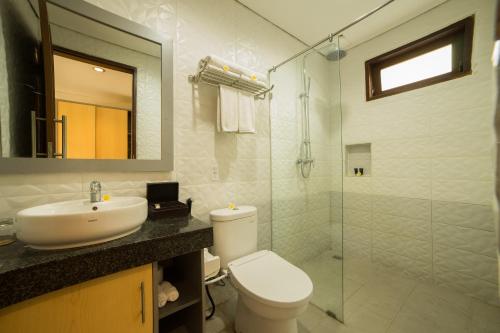 a bathroom with a toilet and a sink and a shower at Grand Kesambi Resort and Villas in Kerobokan