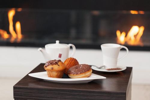 a table with two plates of donuts and cups of coffee at Résidence la Réserve Genève Ferney Voltaire in Ferney-Voltaire
