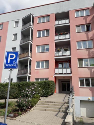 een roze gebouw met een parkeerbord ervoor bij apartmán Peškova in Olomouc