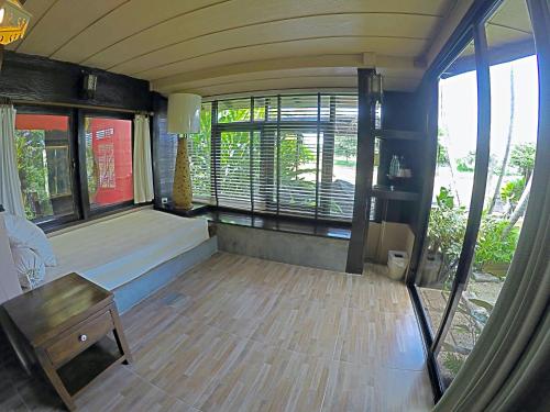 a room with a bed and a table and windows at The Riverside Guest House in Lampang