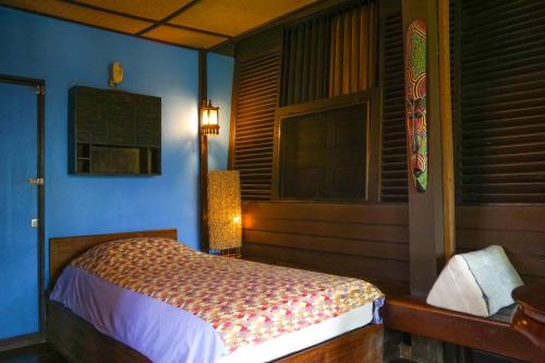 a bedroom with a bed in a blue room at The Riverside Guest House in Lampang