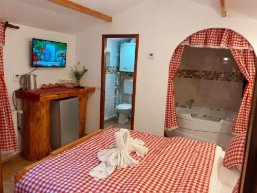 1 dormitorio con cama roja y blanca y bañera en CABANUTE si CAMPING DRACULA, en Căpăţîneni-Pămînteni