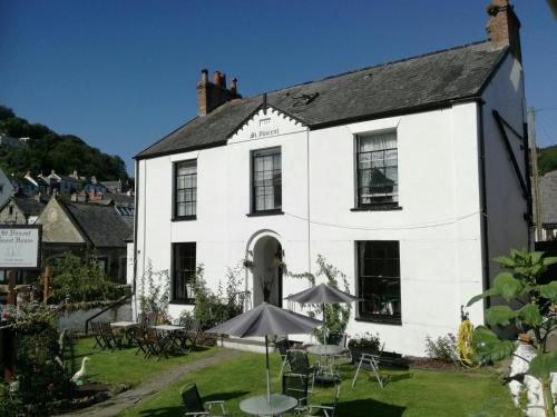 un edificio bianco con tavoli e ombrelloni di fronte di St Vincent Guest House a Lynton