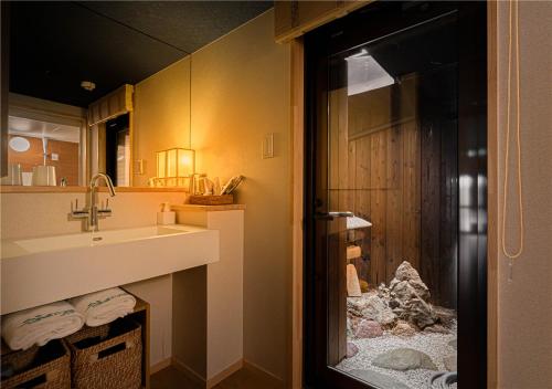 uma casa de banho com um lavatório e uma porta para um chuveiro em 谷町君・星屋・秋の家 em Quioto