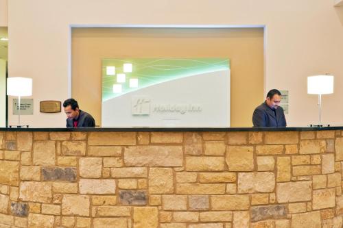two men standing behind a stone wall at Holiday Inn Temple - Belton by IHG in Temple