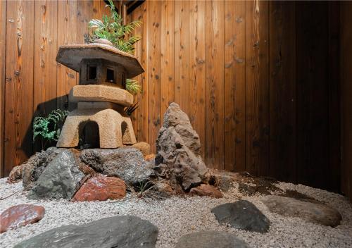 um jardim com uma torre de pedra em frente a uma cerca em 谷町君・星屋・秋の家 em Quioto